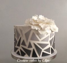 a white and black cake with flowers on top is shown in this image, it looks like an art deco design