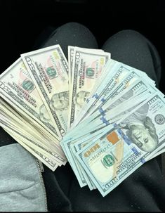 a pile of money sitting on top of a person's lap in the back seat