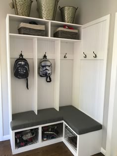 a white bench with two storage bins and some baskets on the wall behind it