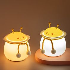 two little lights that are sitting on top of a wooden stand, one is yellow and the other is white