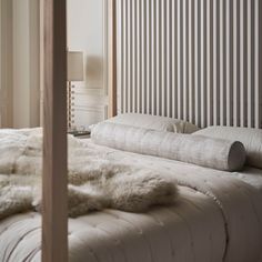 a bed with white fur on top of it in a bedroom next to a lamp