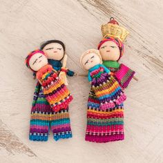 two knitted dolls sitting next to each other on a wooden surface with one holding a stick