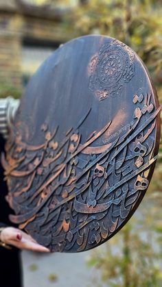 a close up of a person holding a metal object with writing on the outside and inside