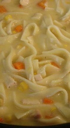 a pot filled with noodles and carrots on top of a stove