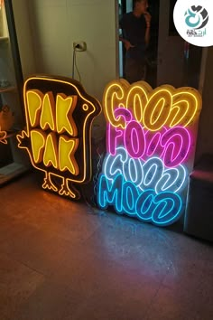 two neon signs sitting next to each other on the floor in front of a mirror