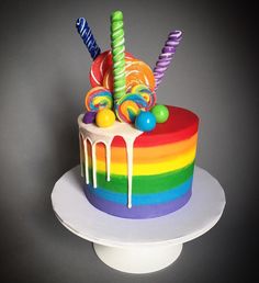 a rainbow cake with candy and lollipops on top