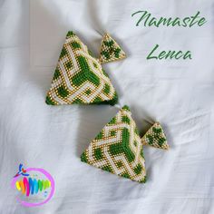 three green and white beaded triangle ornaments on a white sheet with the words nammste lenca