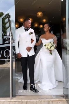 a man and woman in formal wear walking out of a glass door