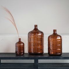 three brown glass vases sitting on top of a wooden table next to each other