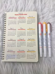 three pens are sitting next to a calendar