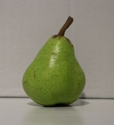 a green pear sitting on top of a white counter