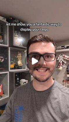 a man with glasses is standing in front of a wall full of legos and toys