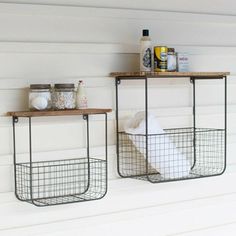 two wire baskets are on the wall next to each other, one is holding toilet paper