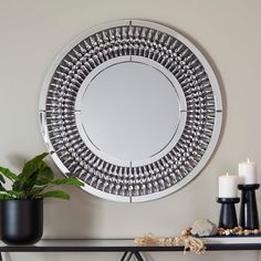 a round mirror sitting on top of a table next to a potted plant and candle