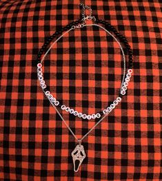 a black and white checkered shirt with two necklaces on it