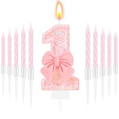 a pink birthday cake with candles in the shape of number one on white background photo