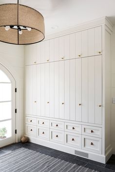 an empty room with white cabinets and a large round light fixture hanging from the ceiling