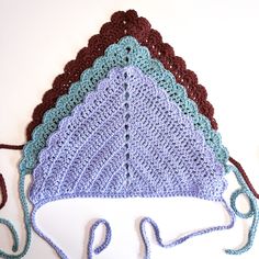 three crocheted hats sitting next to each other on top of a white surface