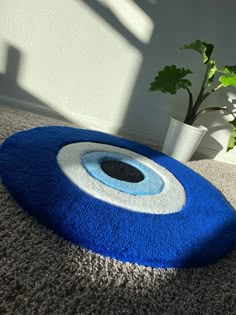 a blue and white rug with an evil eye design on the floor next to a potted plant