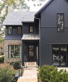 a large gray house with two story windows and stone steps leading up to the front door