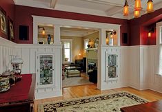 a living room with red walls and white trimmings on the wall, along with wood flooring