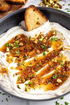 a bowl filled with hummus and bread on top of a white countertop next to other food items