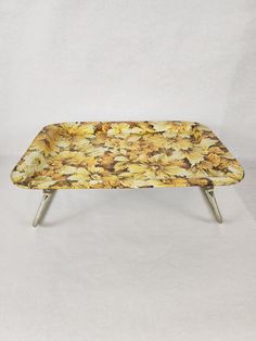 a yellow flowered bench with metal legs