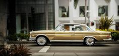 an old car is parked on the side of the road in front of a building