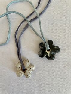 two black and white flowers on a blue cord with one flower in the middle,