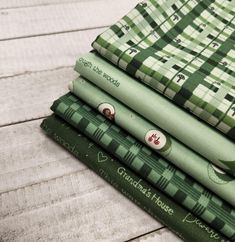 a stack of green wrapping paper sitting on top of a wooden table next to each other