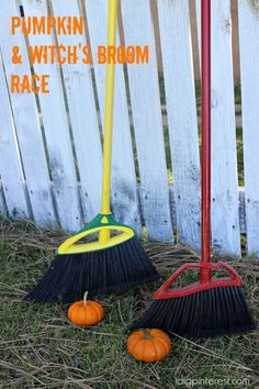 two brooms are sitting in the grass next to a white picket fence with pumpkins and witch's broom