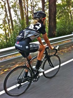 a person riding a bike on a road with trees in the background