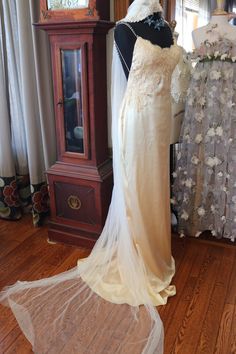 a wedding dress on display in front of a grandfather clock