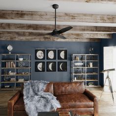 a living room with blue walls and leather couches in front of a wooden ceiling fan