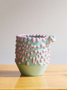 a green and pink vase sitting on top of a wooden table