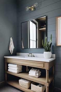 a bathroom with blue walls and white counter tops, wooden cabinets and a large mirror above the sink