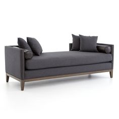 a gray couch with two pillows on it and some dark colored cushions in the back