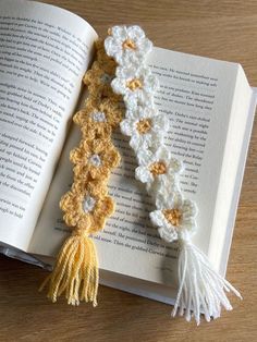 an open book with crocheted flowers and tassels