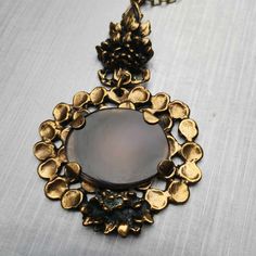 Pentti Sarpeneva was known for his bold designs cast in bronze often described as Brutalist and lived from 1925-1978. Pendant: 9 x 5.4 cm / 3.55 x 2.13 in. Chain: 60 cm / 24 in. Bronze Medallion Necklace In Brass, Ornate Bronze Jewelry With Antique Finish, Antique Gold Copper Necklace, Antique Finish Brass Necklace With Round Pendant, Antique Gold Cabochon Brass Necklace, Antique Gold Brass Necklace With Cabochon, Antique Hand Cast Jewelry For Formal Occasions, Formal Antique Hand Cast Jewelry, Vintage Bronze Round Pendant Jewelry