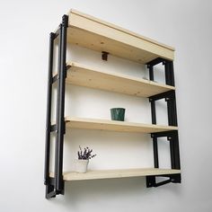 three wooden shelves with black metal brackets on each shelf and a potted plant in the middle