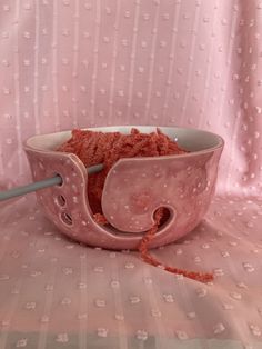 a pink bowl filled with food sitting on top of a table next to a spoon