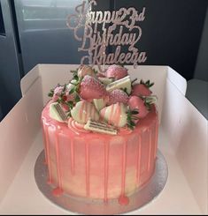 a birthday cake decorated with strawberries and chocolates on a plate in a box