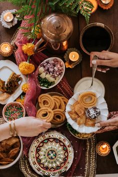 people are serving themselves food on plates at a table with candles and flowers in the background