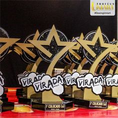 several awards are lined up on a red table with black and gold stars in the background