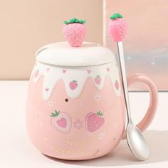 a pink cup with two strawberries on top and a spoon next to it that says sweet strawberry