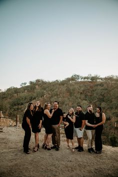 a group of people standing next to each other in front of a hill with trees