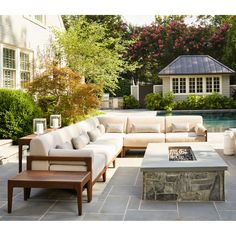 an outdoor living area with couches, tables and a fire pit in the middle