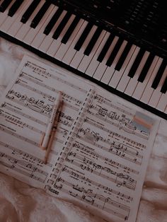 sheet music and pen laying next to piano keyboard