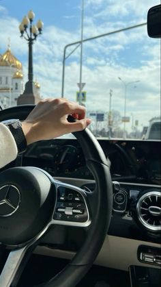 a person driving a car with their hand on the steering wheel