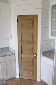 an open door in the corner of a room with white cabinets and granite counter tops